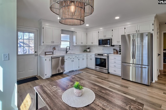 kitchen with light wood-type flooring, a sink, tasteful backsplash, stainless steel appliances, and light countertops