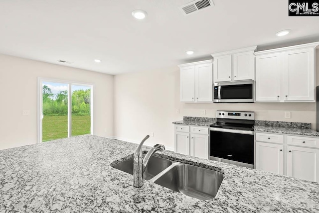 kitchen with a sink, visible vents, appliances with stainless steel finishes, and white cabinets