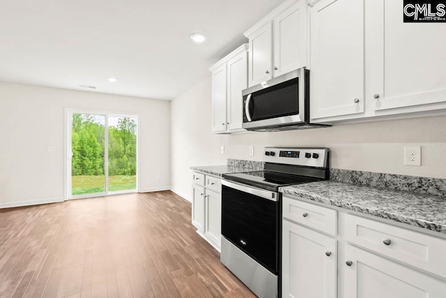 kitchen featuring light stone counters, baseboards, light wood finished floors, stainless steel appliances, and white cabinets