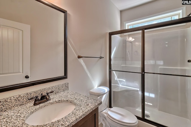 bathroom with a shower stall, toilet, and vanity