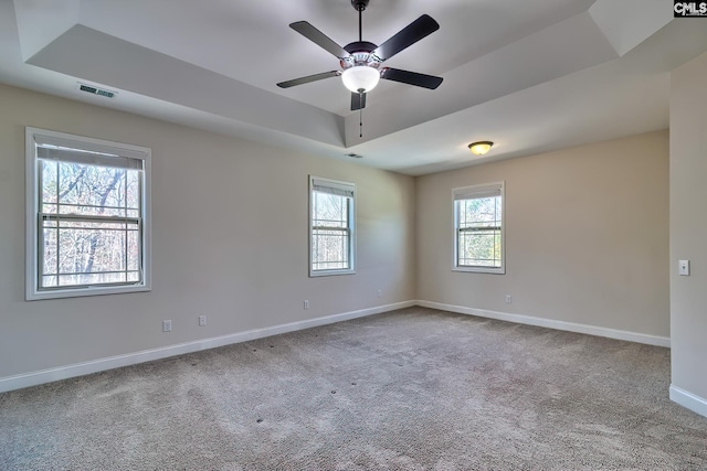 unfurnished room featuring carpet, visible vents, baseboards, ceiling fan, and a raised ceiling