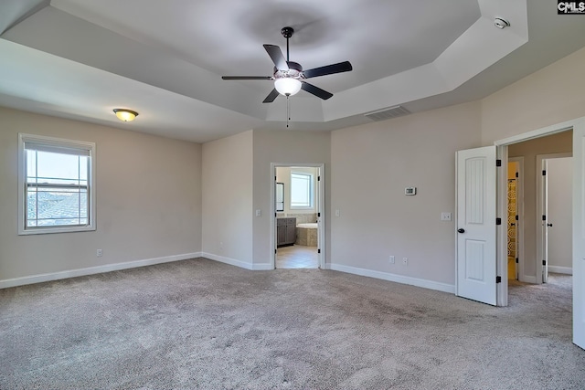 unfurnished bedroom featuring light carpet, visible vents, a raised ceiling, and baseboards