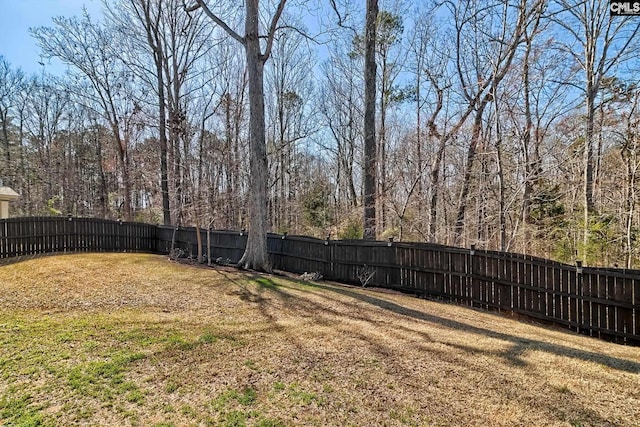 view of yard with a fenced backyard and a wooded view