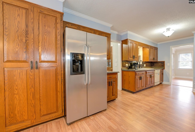 kitchen featuring a sink, stainless steel fridge, brown cabinetry, and white dishwasher