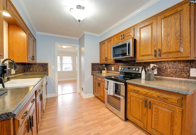 kitchen with a sink, stainless steel appliances, brown cabinets, and dark countertops