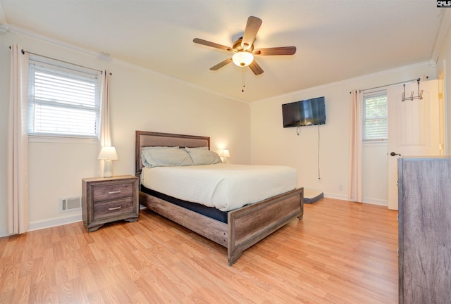 bedroom featuring visible vents, crown molding, light wood-type flooring, and baseboards