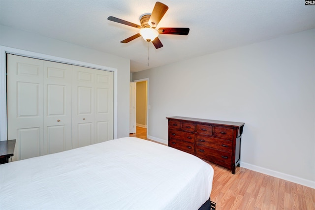 bedroom featuring a closet, baseboards, light wood-style flooring, and a ceiling fan