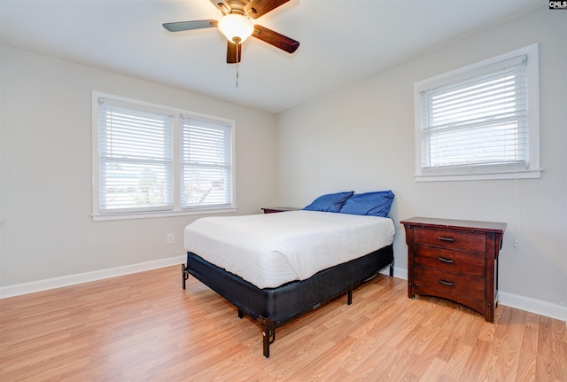 bedroom featuring light wood-style flooring, a ceiling fan, baseboards, and multiple windows