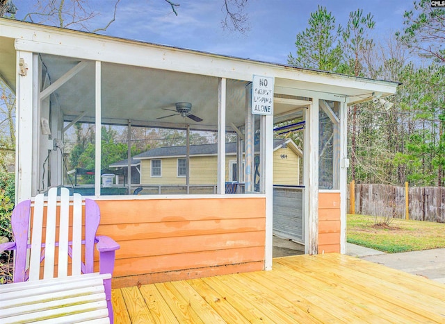 deck with fence, a ceiling fan, and a sunroom