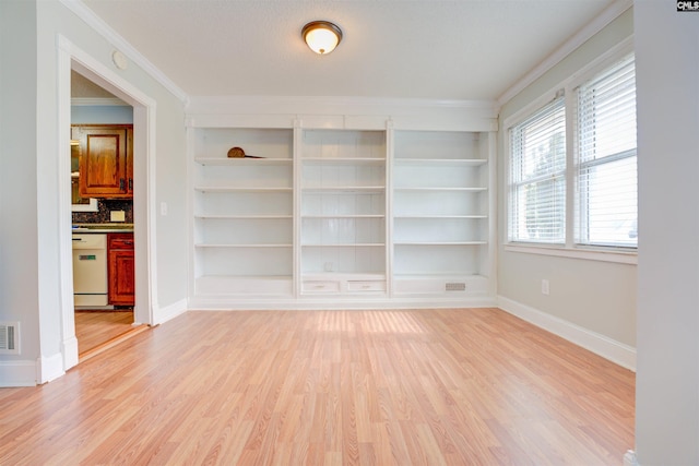 spare room featuring visible vents, baseboards, light wood-style flooring, and crown molding