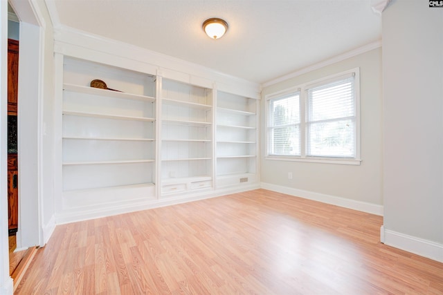 unfurnished room with crown molding, built in features, light wood-style floors, and baseboards