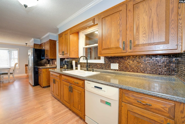 kitchen with dishwasher, ornamental molding, brown cabinets, freestanding refrigerator, and a sink