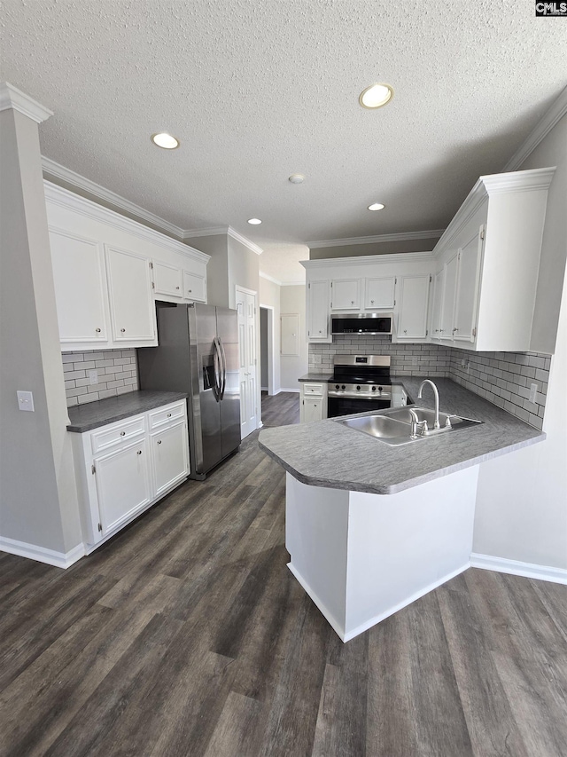 kitchen with a peninsula, dark wood-style flooring, appliances with stainless steel finishes, and a sink