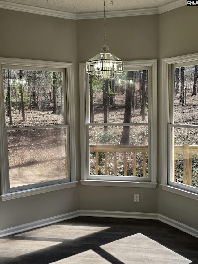 unfurnished dining area with baseboards, a notable chandelier, wood finished floors, and crown molding