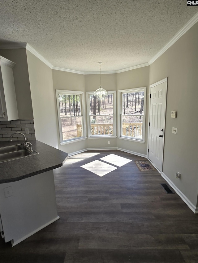 unfurnished dining area with crown molding, dark wood-style flooring, and a sink