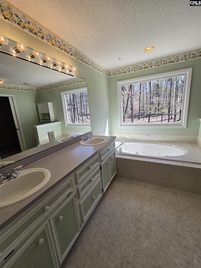 bathroom with a textured ceiling, double vanity, and a sink