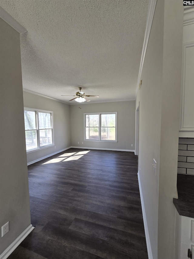 unfurnished living room featuring dark wood-type flooring, a healthy amount of sunlight, a ceiling fan, and crown molding