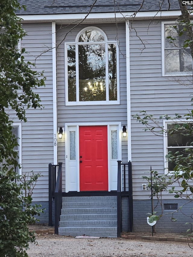 doorway to property featuring roof with shingles