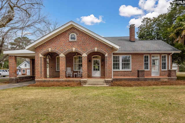 view of front of home with brick siding, an attached carport, a front yard, covered porch, and driveway