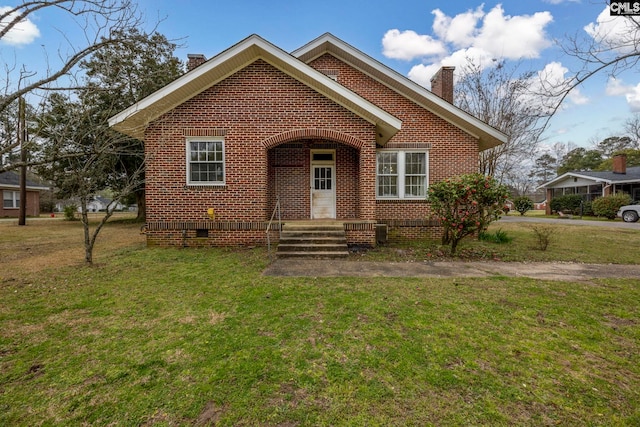 view of front of property with a front yard, brick siding, and a chimney