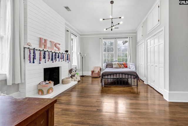 bedroom featuring an inviting chandelier, wood finished floors, visible vents, and ornamental molding