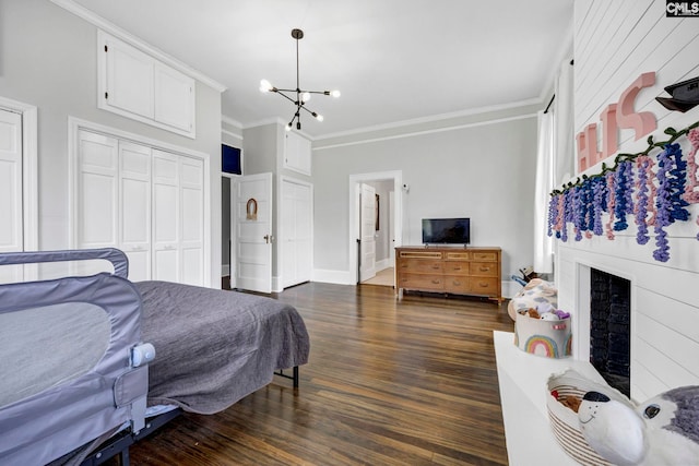 bedroom featuring a notable chandelier, dark wood finished floors, a closet, a fireplace, and crown molding