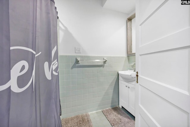 bathroom with a wainscoted wall, a shower with curtain, tile walls, tile patterned flooring, and vanity