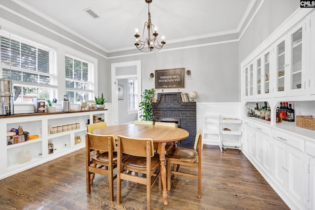 dining room with visible vents, dark wood-type flooring, an inviting chandelier, and crown molding