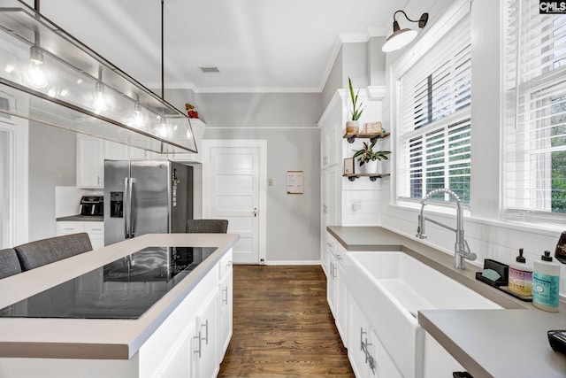 kitchen with stainless steel refrigerator with ice dispenser, a sink, white cabinets, crown molding, and dark wood-style flooring