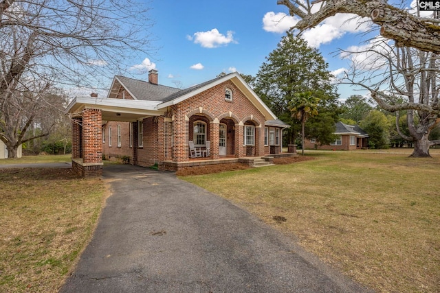 view of front of property with a chimney, a front lawn, driveway, a carport, and brick siding