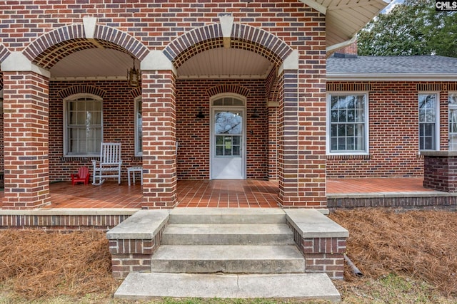 entrance to property featuring brick siding and a porch