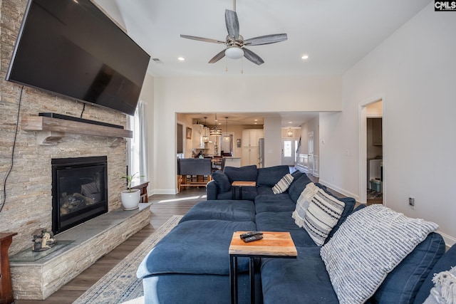 living area with a ceiling fan, wood finished floors, baseboards, and a fireplace