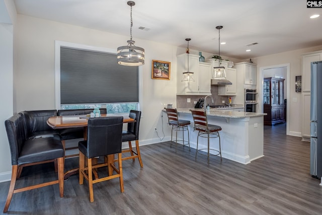 dining room featuring dark wood-type flooring, baseboards, visible vents, and a chandelier