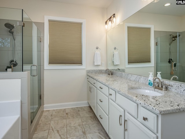 full bath featuring a sink, baseboards, double vanity, and a shower stall