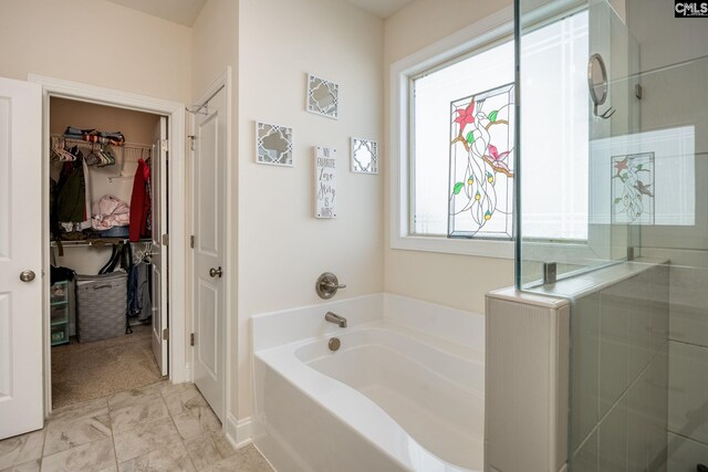 full bath featuring a walk in closet, a bath, marble finish floor, and a tile shower