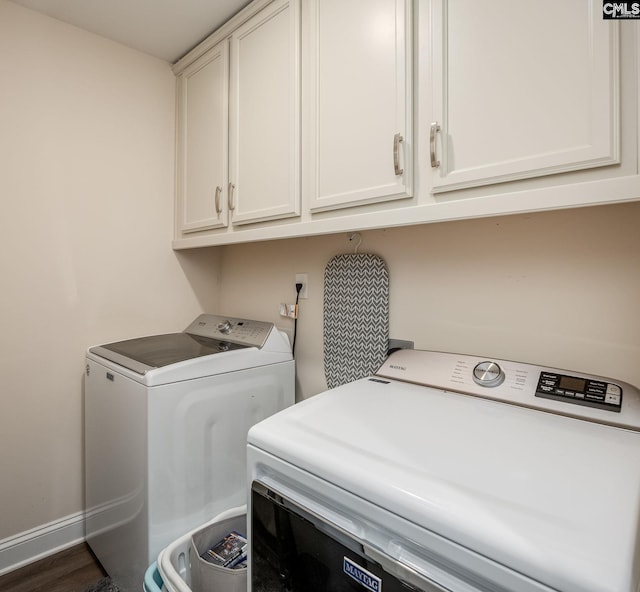 clothes washing area featuring baseboards, cabinet space, dark wood-style floors, and washer and clothes dryer