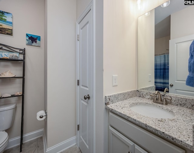 bathroom featuring toilet, vanity, and baseboards