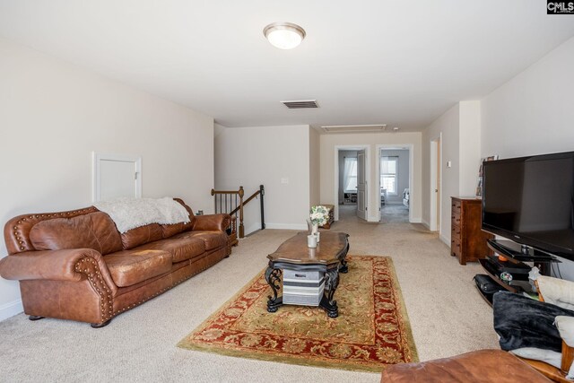 living room featuring light colored carpet, visible vents, and baseboards