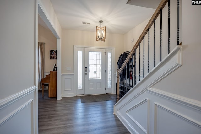 entryway with visible vents, a decorative wall, stairway, wood finished floors, and a notable chandelier