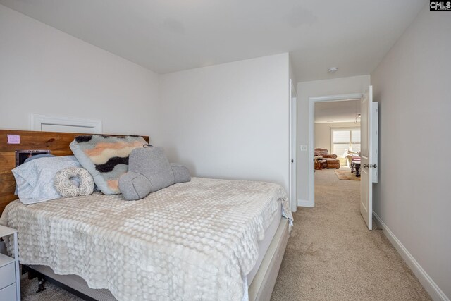 bedroom with baseboards and light carpet