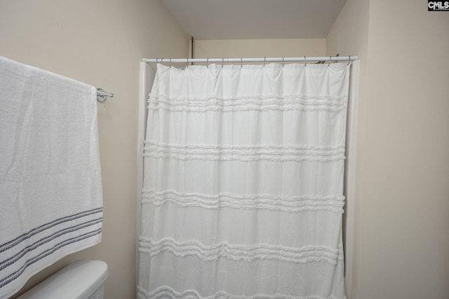 bathroom featuring a shower with curtain and toilet