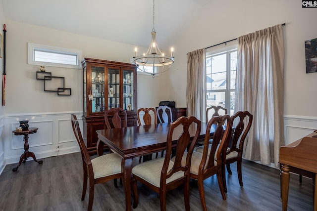 dining area featuring dark wood-style floors, a wainscoted wall, lofted ceiling, a decorative wall, and a notable chandelier