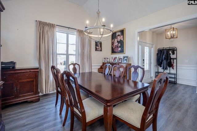 dining room featuring lofted ceiling, dark wood-type flooring, an inviting chandelier, and wainscoting