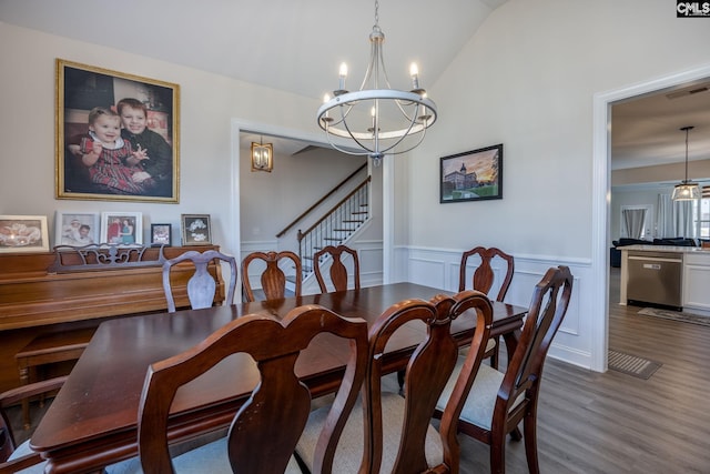 dining area with visible vents, a wainscoted wall, a notable chandelier, wood finished floors, and lofted ceiling