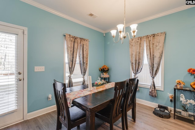 dining room featuring wood finished floors, baseboards, visible vents, ornamental molding, and a chandelier