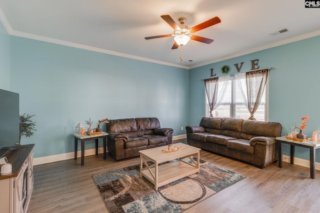 living area with visible vents, ornamental molding, light wood-style flooring, baseboards, and ceiling fan