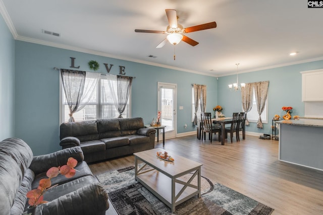 living area featuring light wood-type flooring, baseboards, crown molding, and ceiling fan with notable chandelier