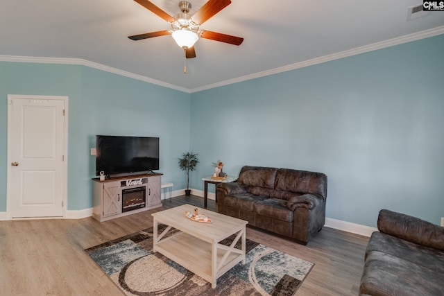 living area featuring ceiling fan, baseboards, wood finished floors, and crown molding