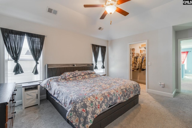 bedroom featuring a spacious closet, visible vents, light colored carpet, and baseboards