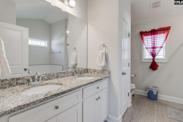 bathroom featuring double vanity, toilet, visible vents, and a sink